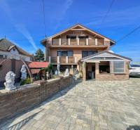 A family house in Dvorníky with a large courtyard, sculptures, and a garage for a car.