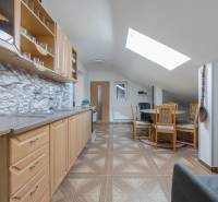 A kitchen in a family house with a wooden decor floor and a gabled roof window.