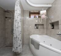 A bathroom with a shower and a bathtub in a family house, walls with ceramic tiles.