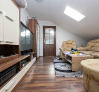 Living room with a sofa, television, and wood-patterned flooring in a family house.