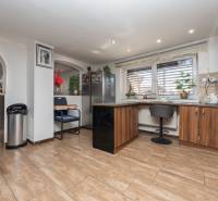 A kitchen in a family house with a pleasant atmosphere, a floor with a wooden decor, bar seating.