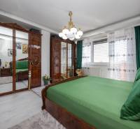 A bedroom in a family house with wooden mirrored wardrobes and green bedding.