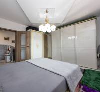 A bedroom with a bed, a white wardrobe, carpets, and a light in a family house.