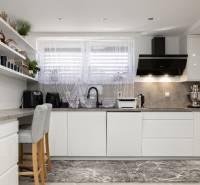 A kitchen in a family house with white furniture, decorative shelves, and stylish appliances.