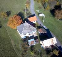 A family house in Malá Lehota surrounded by greenery and an access road.