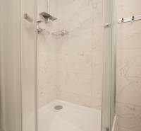 A shower enclosure in the bathroom with white marble tiles in a 3-room apartment.