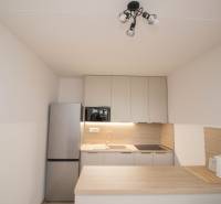 A kitchen in a 3-room apartment with a countertop, refrigerator, and stovetop.