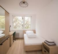 A room in a 3-room apartment with a bed, a table, and a floor with a wooden decor.