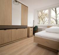 Bedroom in a 3-room apartment with a bed, wardrobe, and floor with wooden decor.