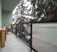 Balcony of a 3-room apartment with furniture and railing, view of greenery.