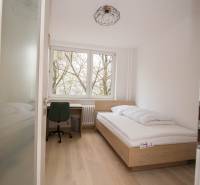 A single bedroom with a bed, a desk, and a wooden floor decor in a three-room apartment.