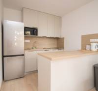A kitchen in a 3-room apartment with a wooden decor floor and modern appliances.