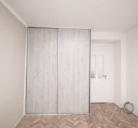 A wardrobe with sliding doors in a two-room apartment, a floor with a wooden decor.