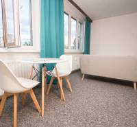 Living room with a table and chairs in a 4-room apartment, bright curtains, light carpet.