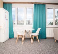 A kitchen with a table and chairs in a 4-room apartment, a wardrobe, and windows with turquoise curtains.