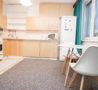 A kitchen with white furniture and a dining table in a 4-room apartment.
