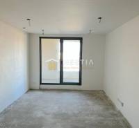An empty room with a concrete floor, a balcony view, and a large window, suitable for a 2-room apartment.