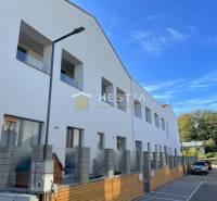 Exterior of an apartment building with parking, surrounding nature, ideal for purchasing a 2-bedroom apartment.