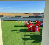 A playground on the roof with green artificial grass and colorful tables and chairs.
