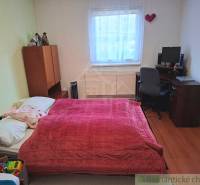 A bedroom in a family house with a bed, a desk, and a wooden decor floor.
