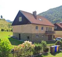A family house in Liptovské Revúce with a red roof, a garden, and a flower fence.