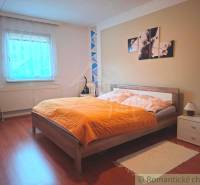 A bedroom in a family house with a bed, decoration, and a floor with a wooden design.