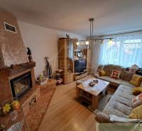 Living room in a family house with a fireplace, sofa, and wooden decor flooring.