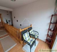 Interior of a family house with a staircase, chairs, and a floor with a wooden decor.