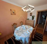 A stylish dining room of a family house, highlighted by a light and neatly arranged tablecloth, as well as a distinctive chandelier.