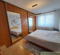 A bedroom in a family house with mirrored wardrobes and a wooden decor floor.