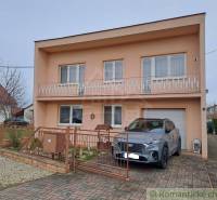 A family house in Veľké Ripňany with a balcony and a car on the driveway.