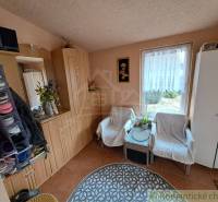 A view into the hallway of a family house with chairs, cabinets, and a window with a view.