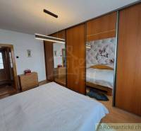 A bedroom in a family house with a wooden decor floor and a large wardrobe.