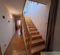 A hallway of a family house with wooden stairs and a floor with a wooden decor.