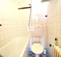 A bathroom in a family house with a bathtub, toilet, and tiled walls.