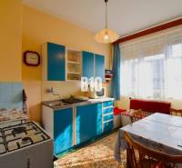 A kitchen in a family house with a blue kitchen unit, a gas stove, and a dining table.