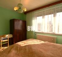 A bedroom in a family house with a window, curtains, a wardrobe, and a table.