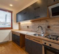 A kitchen in a 5 or more room apartment with an elegant kitchen unit and a wooden decor floor.