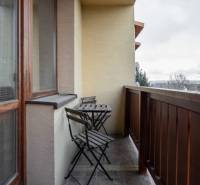 A balcony with a wooden railing and a table with two chairs in a 5 or more room apartment.