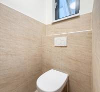 A restroom with natural tiling in commercial premises, simple design and a window.