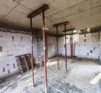 The interior of the cottage under construction with temporary supports, exposed bricks, and building material.