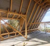 An unfinished cabin with a wooden structure at Zajačia debra in Holčíkovce, overlooking the river.
