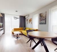 Living room in a 3-room apartment with a sofa, light curtains, and a wooden decor floor.