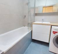 Bathroom with a bathtub, sink, mirror, and washing machine in a 3-room apartment.