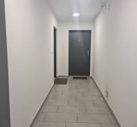 The interior of a hallway with white walls and gray tiles in a 3-room apartment.