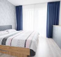 A bedroom in a 3-room apartment with a bed, blue curtains, and a dresser.