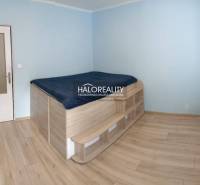 A bedroom with a raised bed and a wooden decor floor in a 3-room apartment.