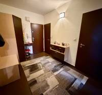A hallway with dark doors, a chest of drawers, and a wooden decor floor in a 3-room apartment.