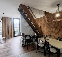 A cottage with a wooden decor floor, a staircase, and a table next to a wall of wooden slats.