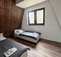 A room with two beds, wooden paneling, and a floor with a wooden decor in a cabin.